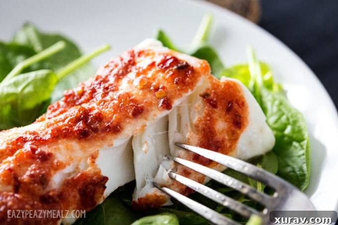 A fork lifting a piece of flaky baked haddock.
