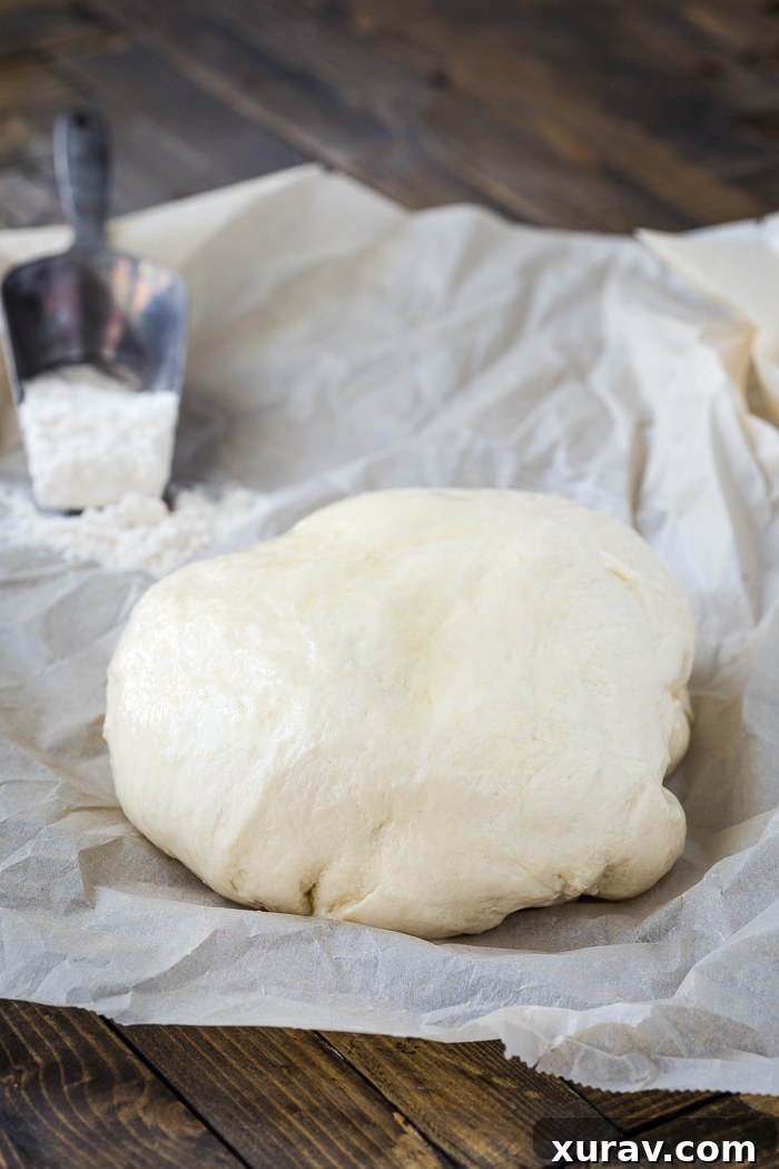 Smooth, elastic homemade naan dough resting on wax paper, perfectly prepared for its first rise, a key step in naan making.