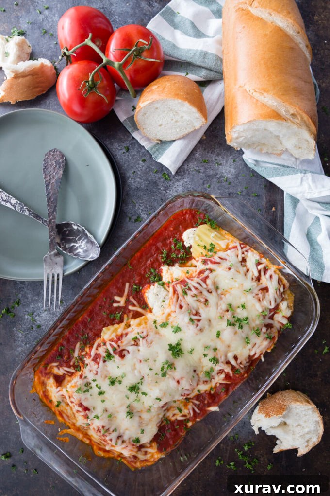 A glass baking dish of stuffed manicotti with French bread and fresh tomatoes