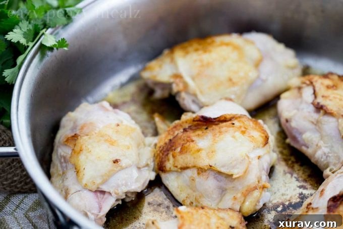 Closer view of the cooked Thai peanut chicken thighs in a cast iron skillet, golden brown and saucy.