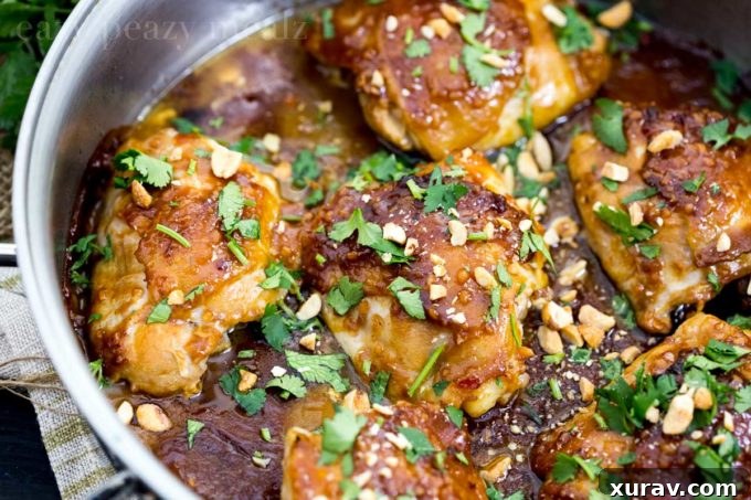 Plated Thai peanut skillet chicken, served with white rice and green beans, garnished with peanuts and cilantro.