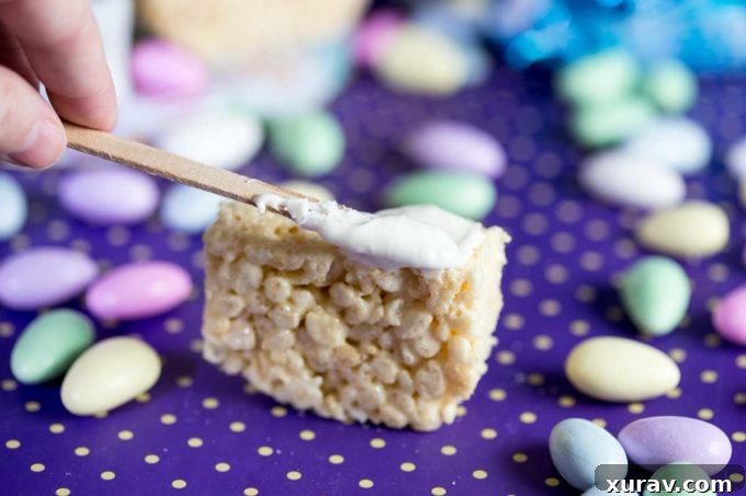 Step 2: Spreading melted white chocolate onto the shaped Rice Krispies Treat bar, preparing it for decoration.