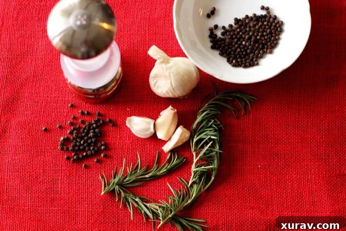 Fresh ingredients laid out: 10 garlic cloves, fresh rosemary, salt, pepper, olive oil, and a filet mignon steak, ready for marinade preparation.