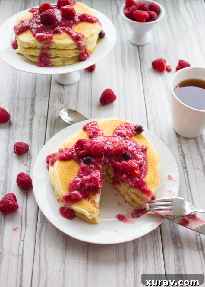 Stack of Raspberry Cheesecake Pancakes with raspberry sauce and fresh berries