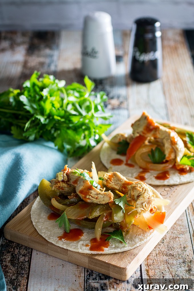 Crock Pot Fajita Chicken, showing fully cooked, shredded chicken with peppers and onions in a slow cooker