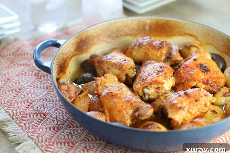 A cast iron skillet filled with golden baked chicken and potatoes, drenched in a creamy lemon garlic sauce, ready for serving.