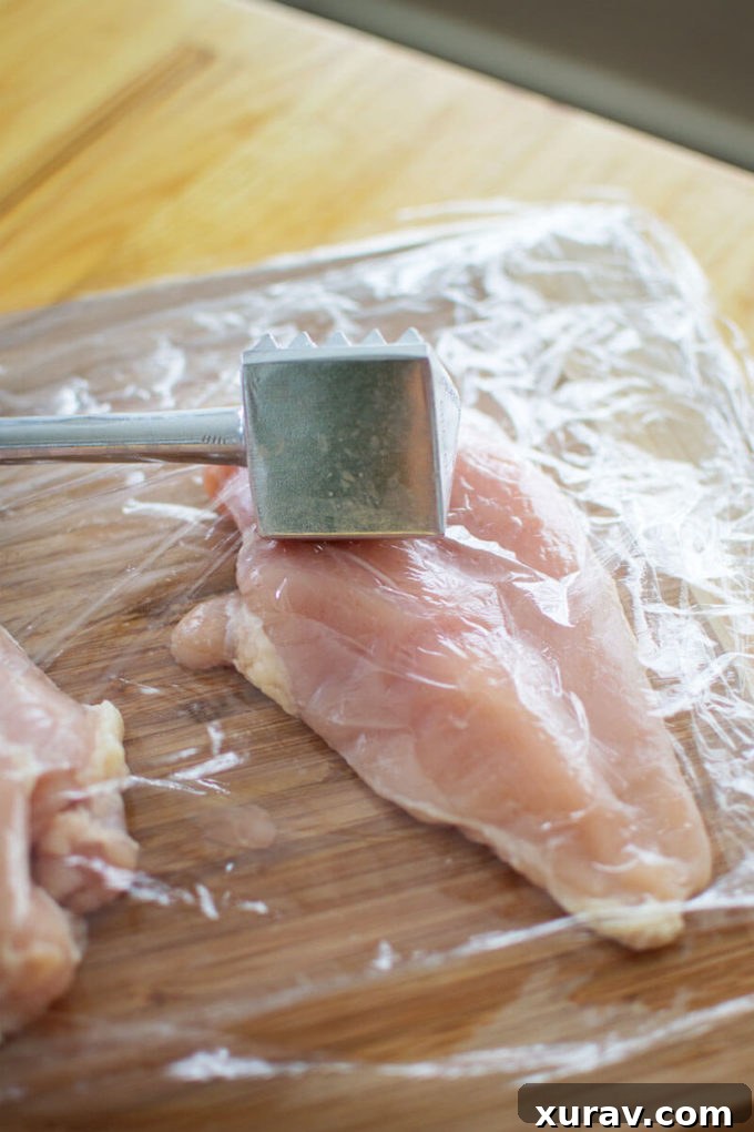 Raw chicken breasts being floured for Lemon Chicken Piccata