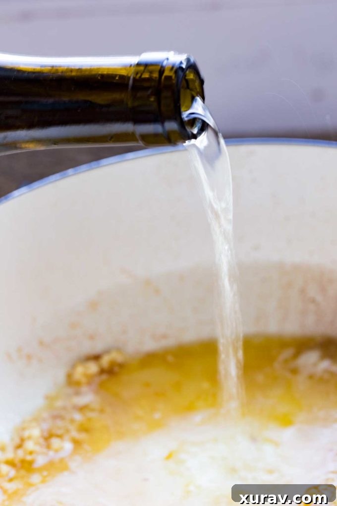 Ingredients for white wine sauce – garlic, lemon, chicken stock, and wine simmering in a skillet
