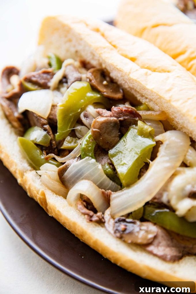 Close-up of Sheet Pan Philly Cheesesteaks filling: Melted cheese, tender beef, and colorful vegetables.