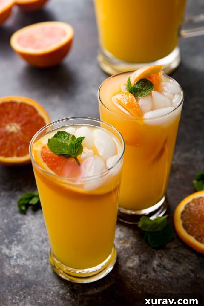 Three glasses of Mango Orange Mojito, each garnished with fresh mint and orange slices, on a light background, emphasizing their refreshing appeal.