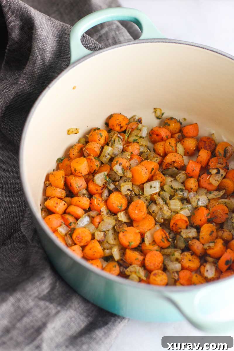 A large pot of creamy orzo chicken soup simmering on the stove, filled with tender chicken, pasta, and vegetables.