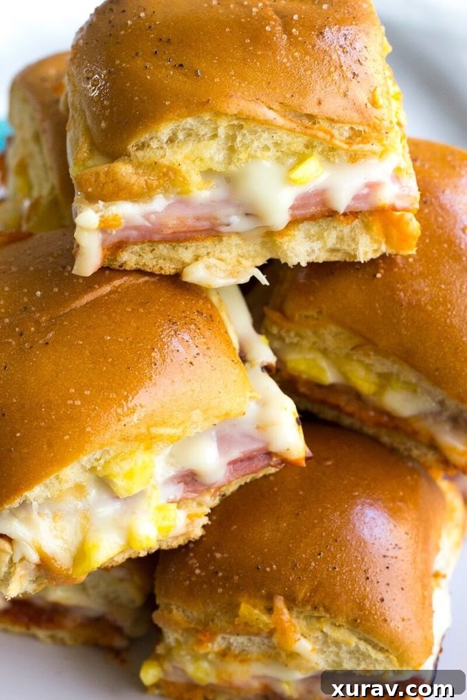 A plate full of freshly baked Hawaiian Pizza Sliders, garnished with a sprinkle of fresh herbs.