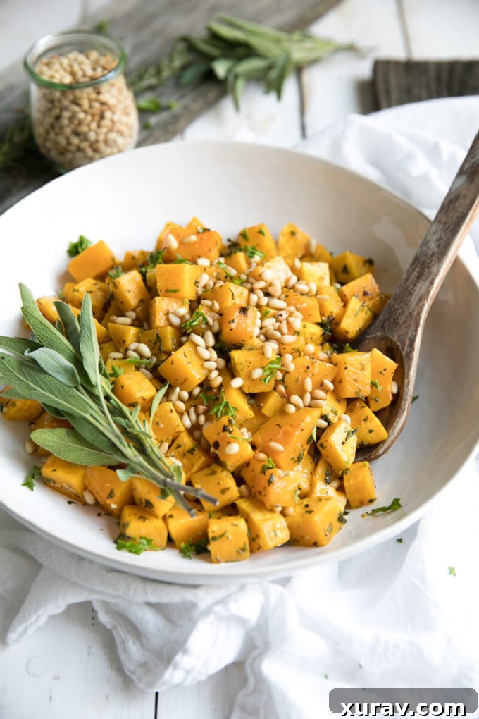 Close-up of golden brown oven roasted butternut squash with garlic, herbs, and pine nuts