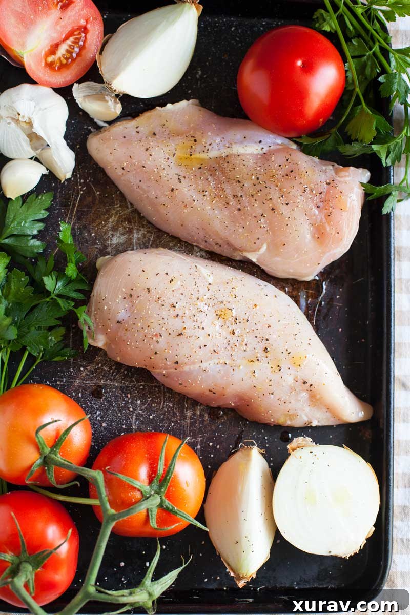 Close-up of golden brown roast chicken alongside roasted tomatoes and onions on a sheet pan, ready for sauce blending.