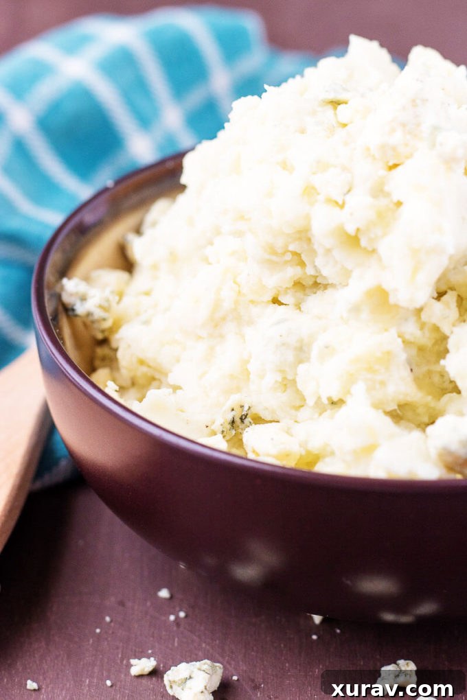 Roasted Garlic Bleu Cheese Mashed Potatoes in a brown bowl with a blue towel, ready to be served.