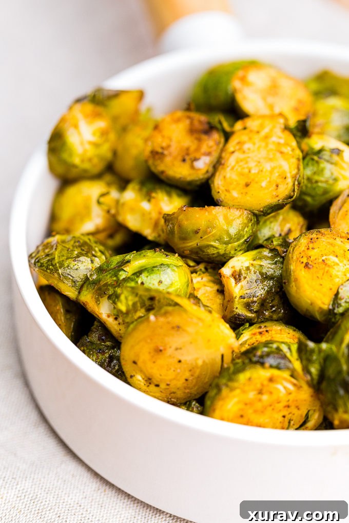 Close-up of crispy, perfectly roasted Brussels sprouts in a bowl, showcasing their vibrant green color and charred edges.