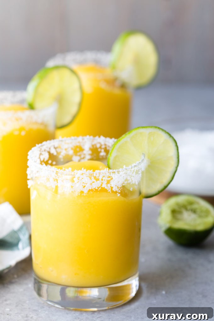 Frozen Mango Margaritas in a glass with a salted rim. 