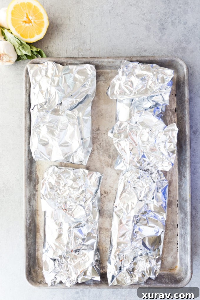 Close up of cooked lemon butter salmon foil packets with asparagus, glistening with sauce