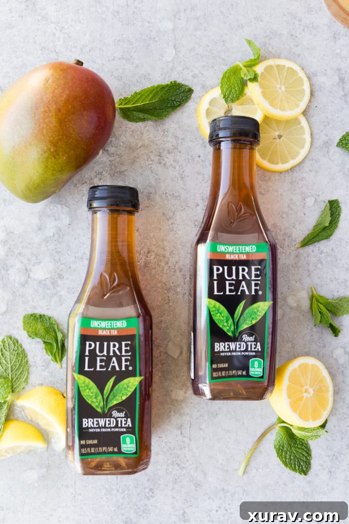 2 bottles of pure leaf black tea, with mangos, and lemon slices around them for making mango black tea lemonade