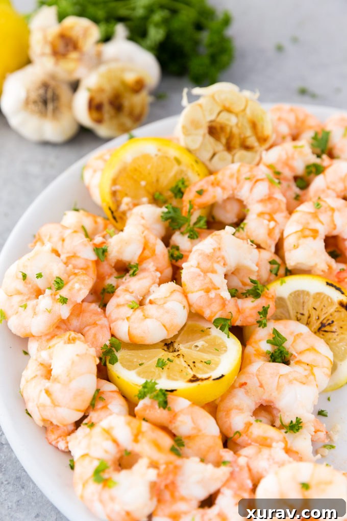 Close-up of garlic butter shrimp in a skillet, garnished with fresh parsley and lemon wedges.