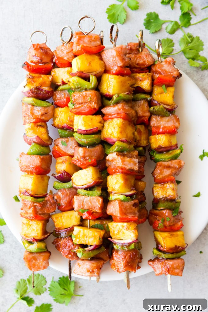 Deliciously sticky BBQ Pork Kabobs, with pineapple, green and red peppers, red onion, and bbq pork, topped with cilantro