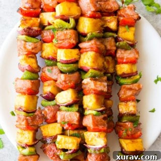Deliciously sticky BBQ Pork Kabobs, with pineapple, green and red peppers, red onion, and bbq pork, topped with cilantro
