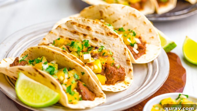 Tacos al pastor with three tacos on a plate, with lime wedges