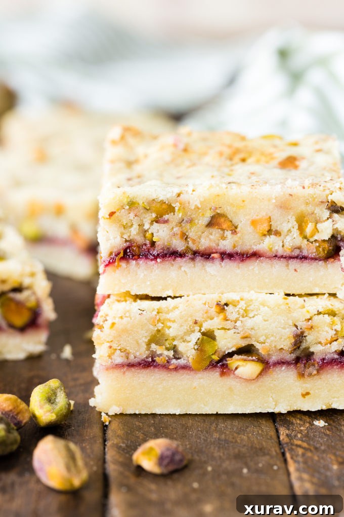 Two perfectly cut raspberry pistachio shortbread bars, ready to be enjoyed.