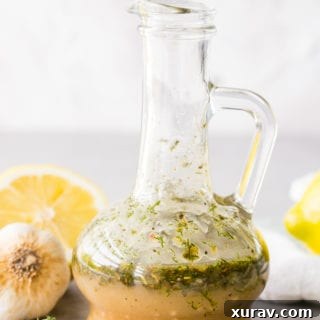 Bottle of Greek Chicken Marinade with lemons, garlic, and herbs around it.