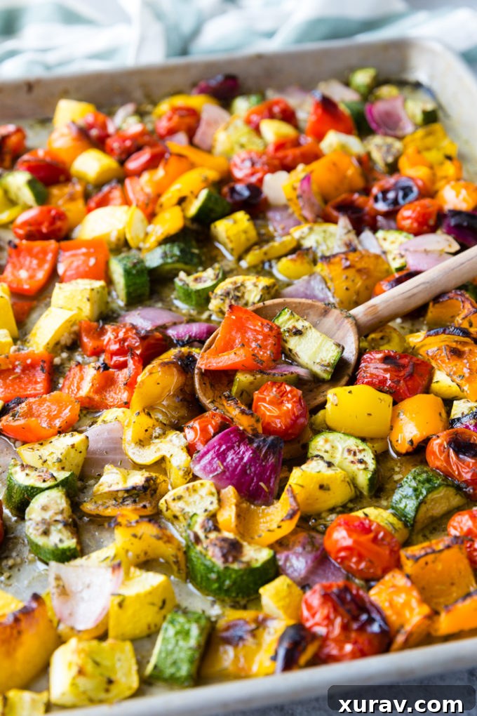 Roasted Greek Vegetables on a sheet pan with a wooden spoon, showcasing vibrant colors.
