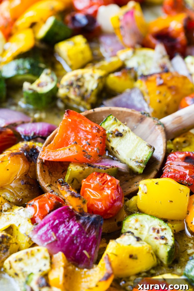 A wooden spoon serving a portion of perfectly roasted Greek vegetables from a sheet pan.