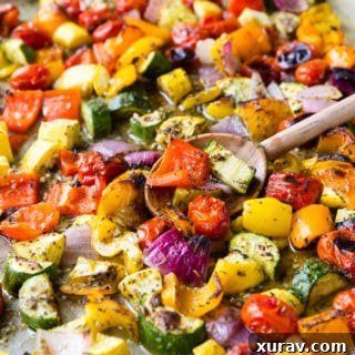 Roasted Greek Vegetables on a sheet pan with a wooden spoon.