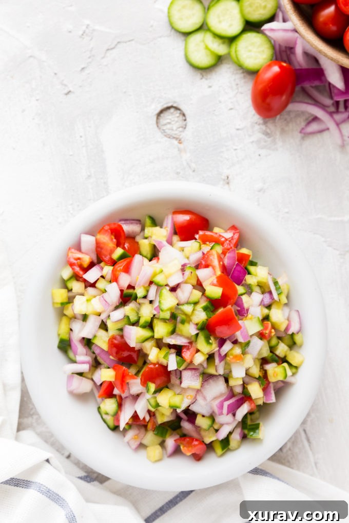 Close-up of fresh cucumber salad with tomatoes, red onion, dill, and feta.