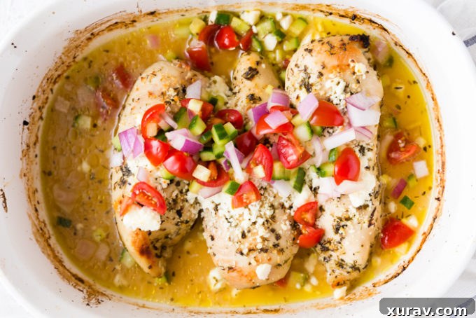 Baked Greek Chicken Breast topped with a colorful cucumber, tomato, and feta salad.