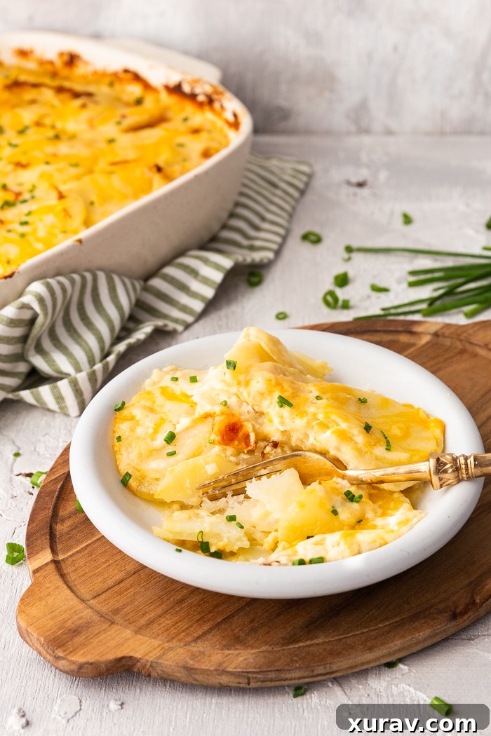 Delicious cheesy scalloped potatoes on a white plate, with a wood trivet under and a green and white striped napkin