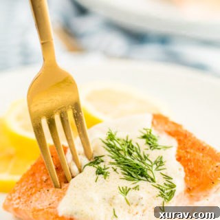 A white plate with creamy lemon dill sauce on salmon