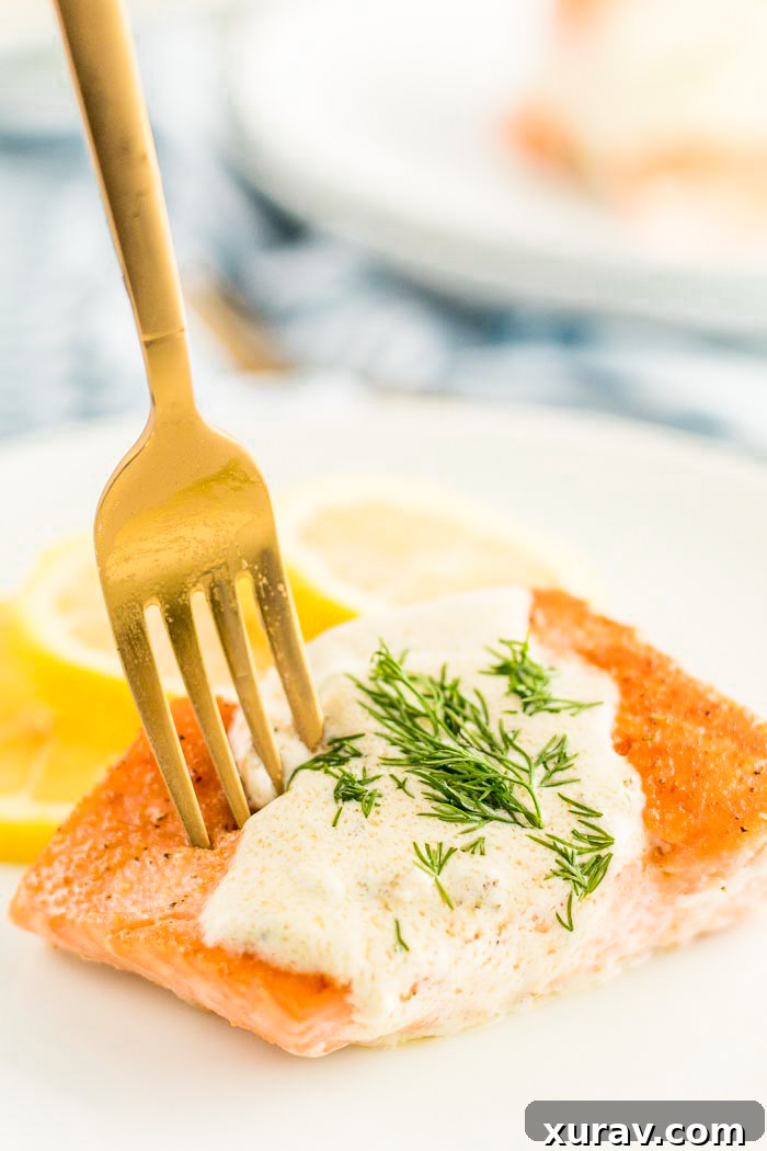 A white plate with creamy lemon dill sauce on salmon