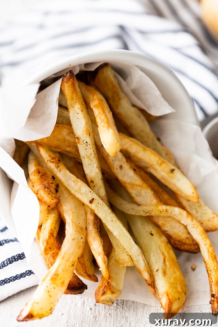 Crispy homemade air fryer French fries piled high on a plate, ready to be served.