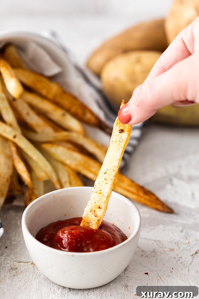 Freshly air-fried French fries being removed from the air fryer basket, steam rising.