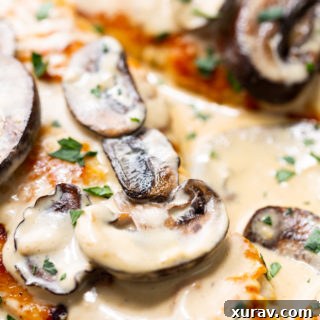 Creamy chicken marsala in a skillet with mushrooms and fresh herbs