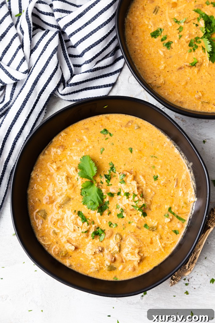 Two bowls of instant pot white chicken chili, bowls are black, striped napkin in corner, soup garnished with cilantro leaves