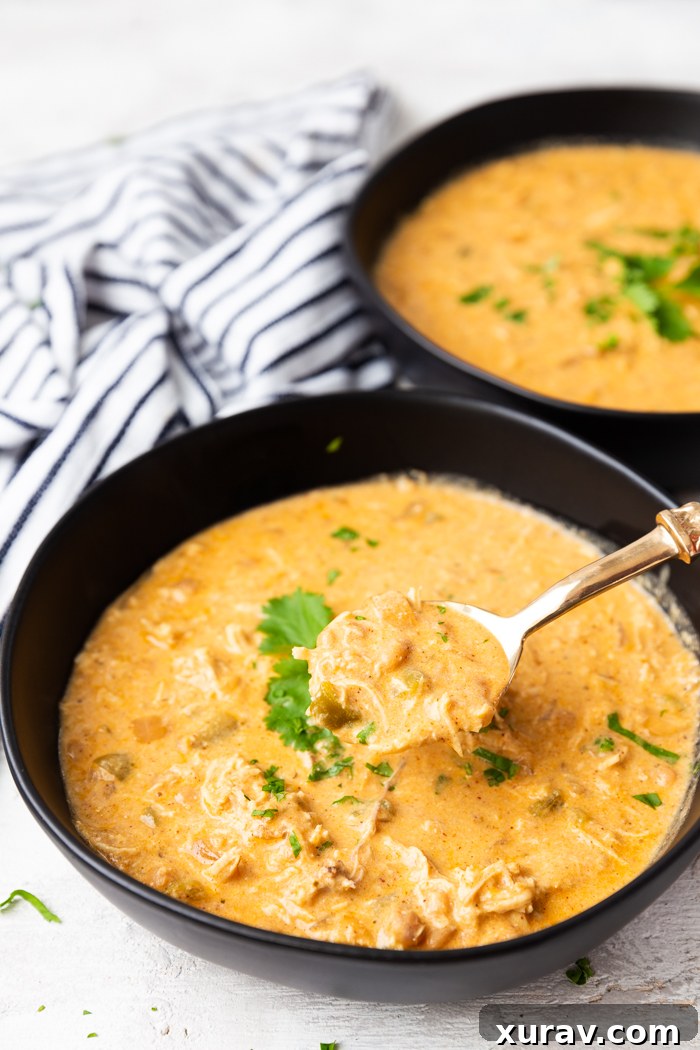 A bowl full of White chicken chili with a spoonful out