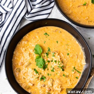 Two bowls of instant pot white chicken chili, bowls are black, striped napkin in corner, soup garnished with cilantro leaves