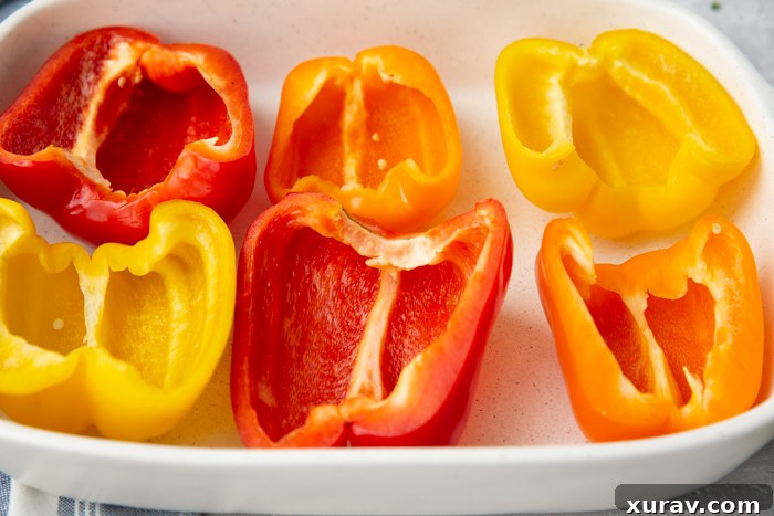 A baking pan with red, orange, and yellow pepper halves
