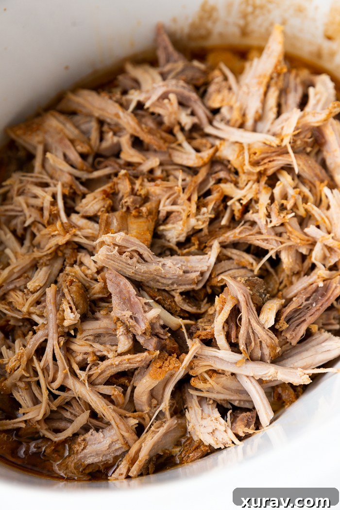 Sweet and Smoky roasted pork shredded and in a white crock pot