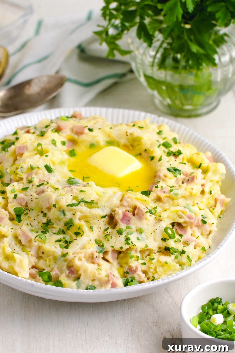 Colcannon in a white bowl with parsley and spoons in the background