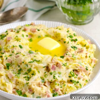 Colcannon in a white bowl with parsley and spoons in the background