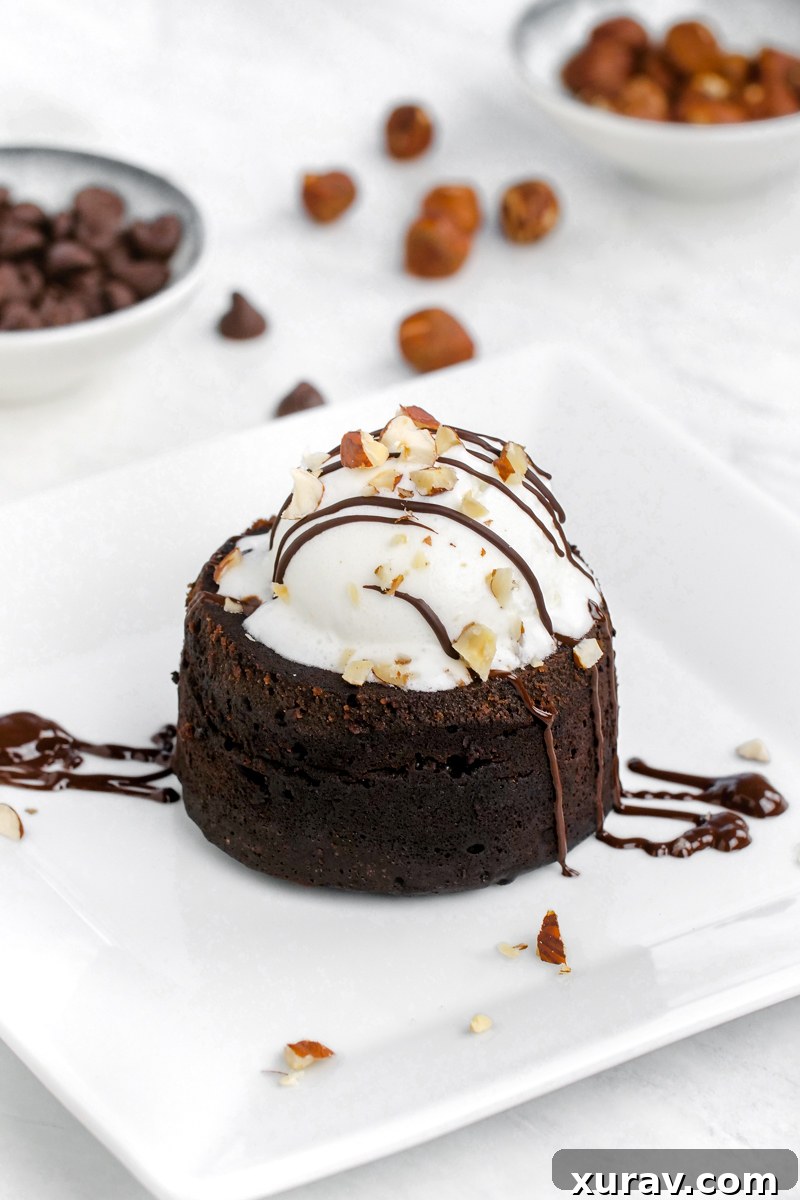 An appetizing Instant Pot lava cake, crowned with a scoop of vanilla ice cream and artfully drizzled with rich Nutella sauce.