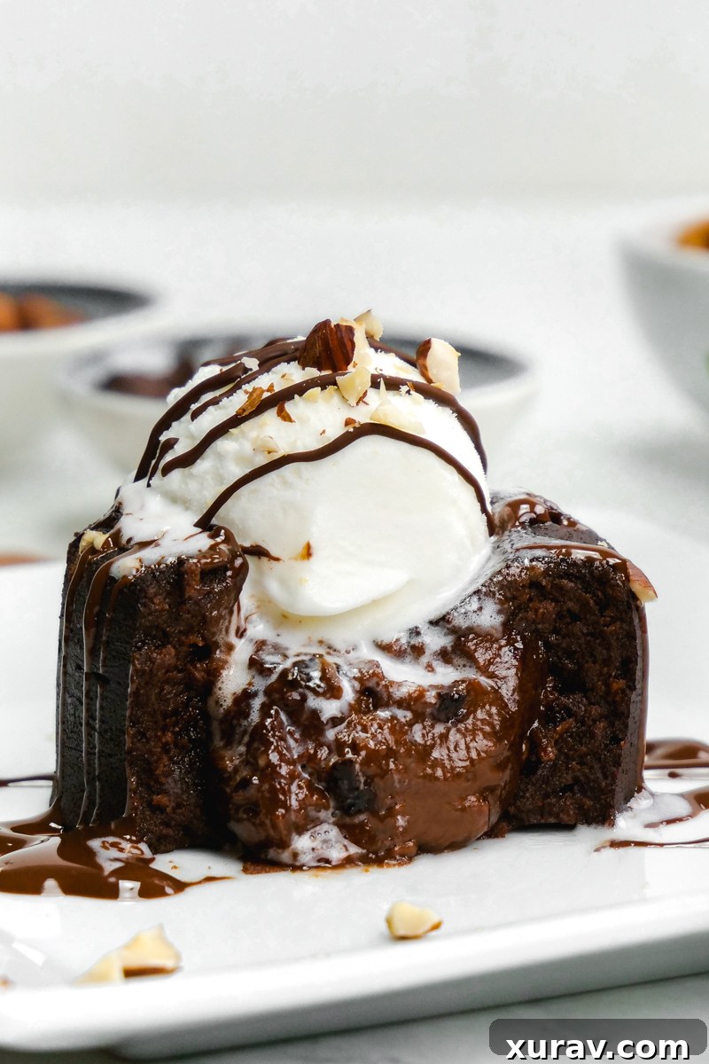 An irresistible Nutella molten lava cake with its creamy center oozing out onto a white plate, served delightfully with a scoop of ice cream.