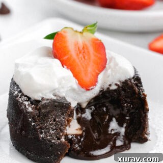 Chocolate molten lava cake with lava flowing, topped with whipped cream and strawberries